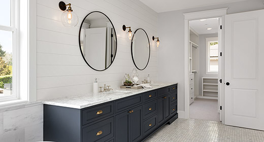 Inside of a nicely renovated bathroom with a large vanity, two mirrors, and a nice tiled floor