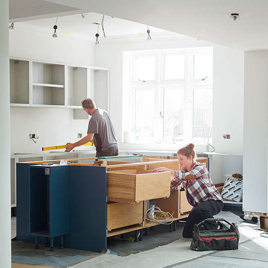 Man and woman renovating kitchen surfaces