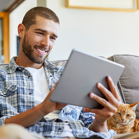 man on his tablet sitting next to his cat 480x480