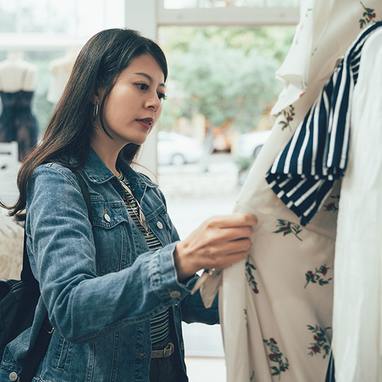 Woman browsing through dresses at a shop