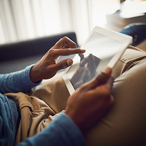 Man sitting on his couch with a tablet device in his hands