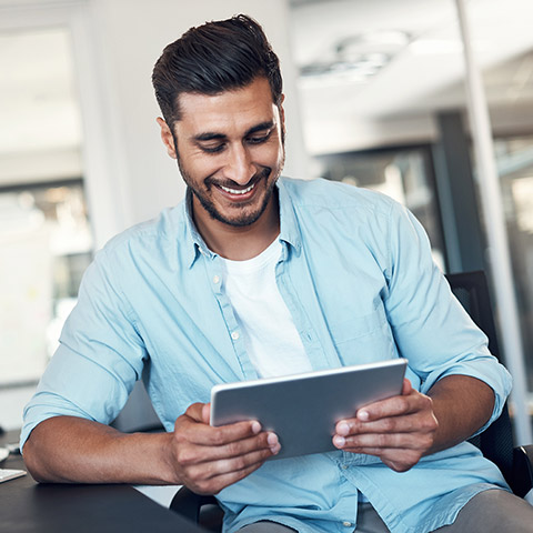 Man smiling and looking at the tablet device he is holding
