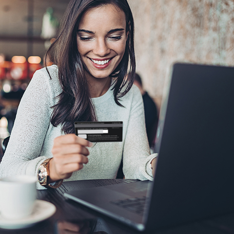 woman holding her credit card while on her laptop