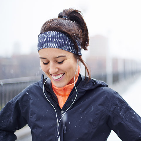 Woman jogging along a snowy road she has stopped to catch her breath